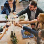 Gruppe von Kollegen bei einem festlichen Abendessen in einer eleganten Firmenevent Location mit Holzfussboden und modernem Ambiente