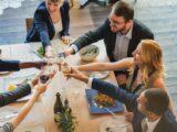 Gruppe von Kollegen bei einem festlichen Abendessen in einer eleganten Firmenevent Location mit Holzfussboden und modernem Ambiente