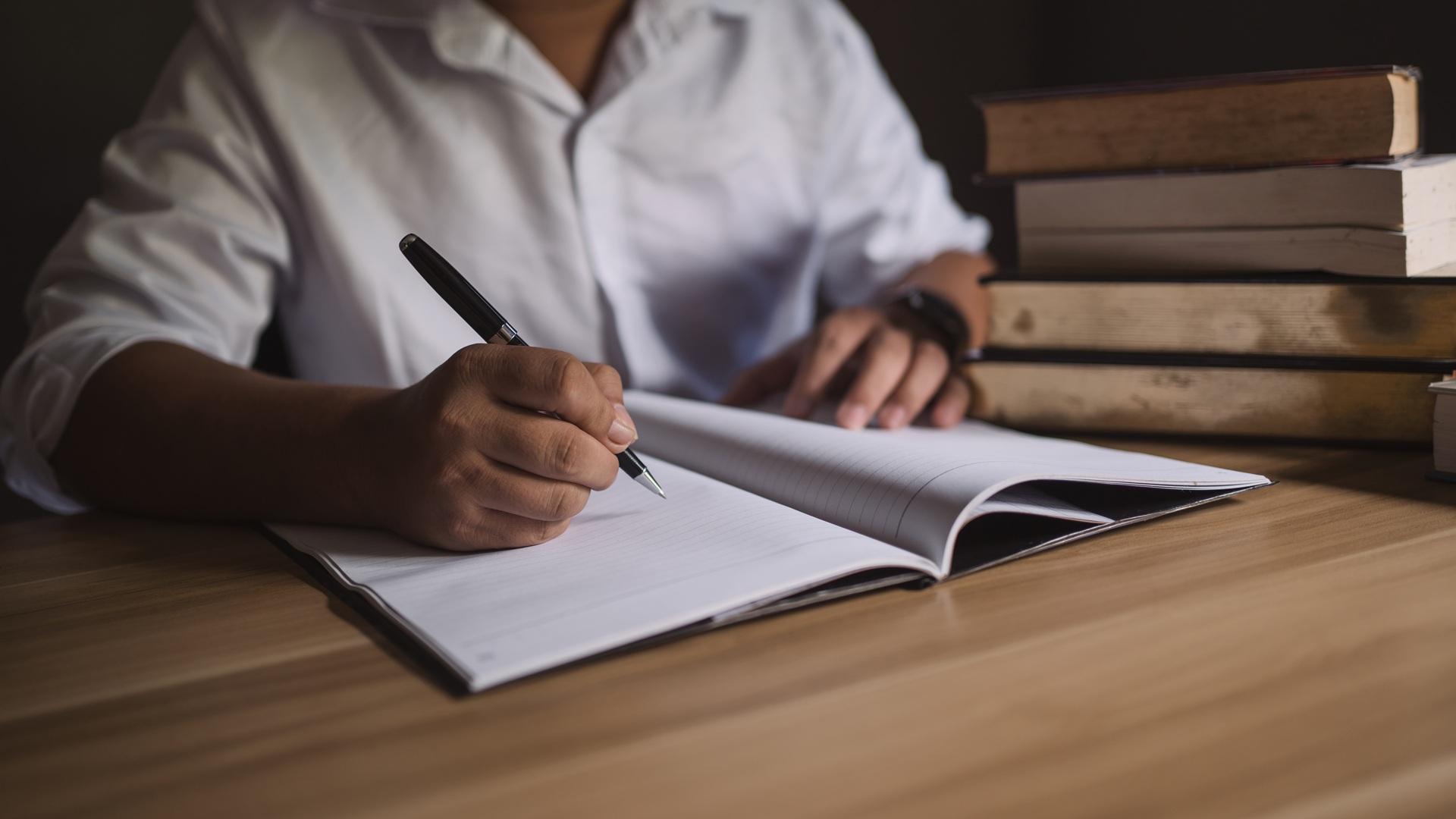 Student schreibt konzentriert in Notizbuch | Bachelorarbeiten schreiben lassen